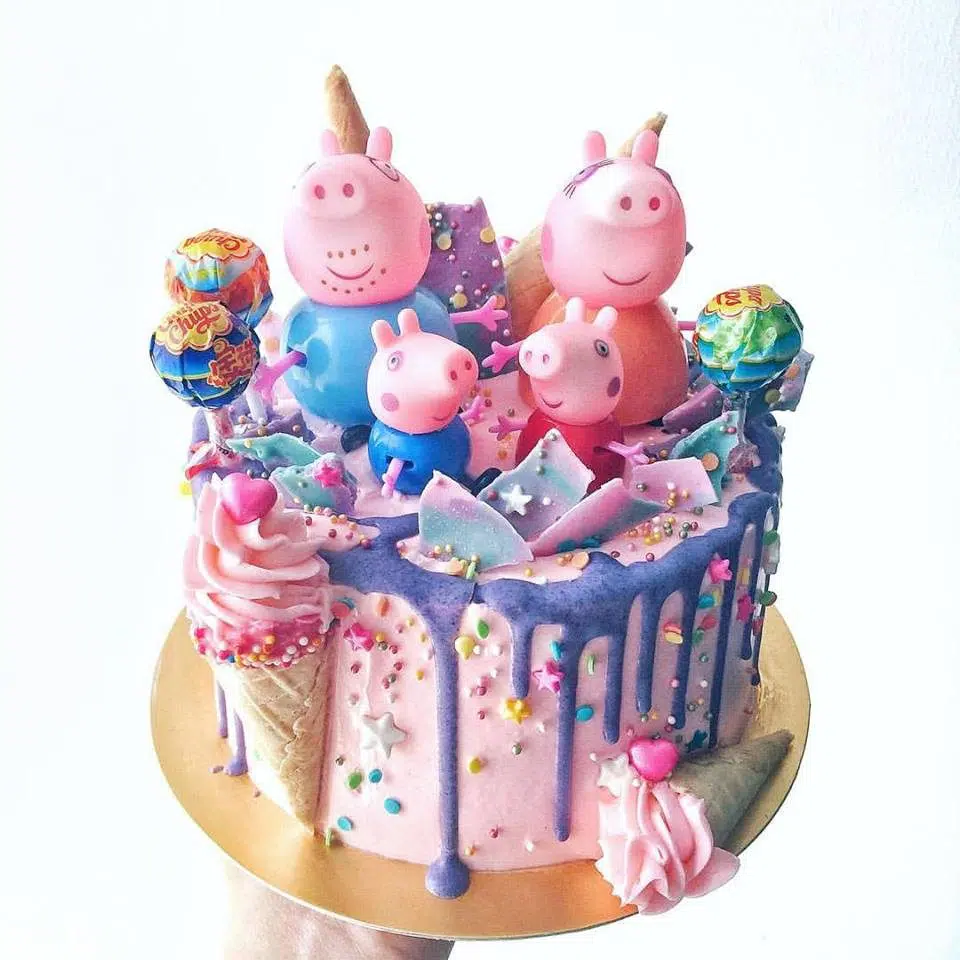 A Peppa Pig themed cake with rainbow coloured frosting, lollipops and figurines. Corine and Cake.Source