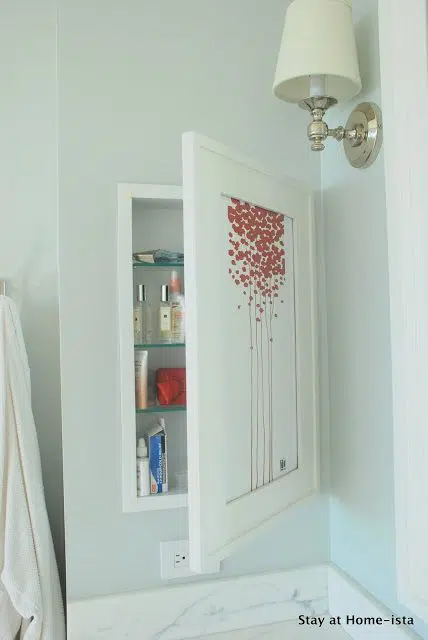 Recessed cosmetics cabinet hidden behind artwork