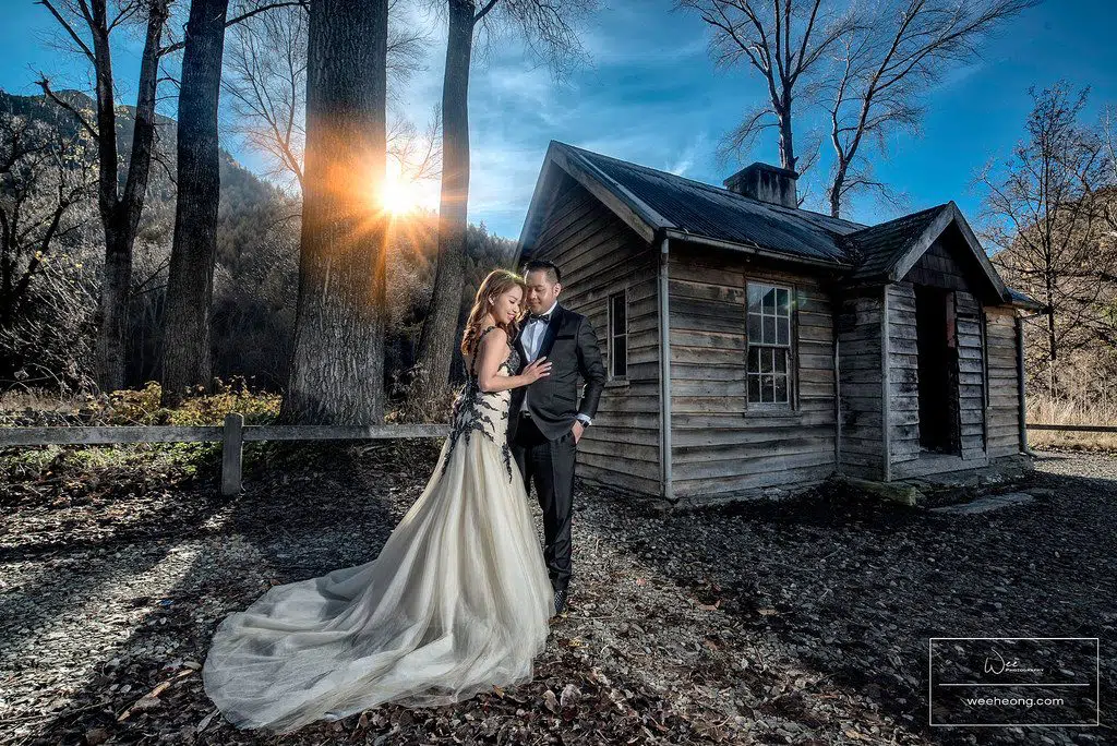 Malaysian wedding couple poses for prewedding photograph by a wooden hut in New Zealand. Photo by Wee Heong Photography