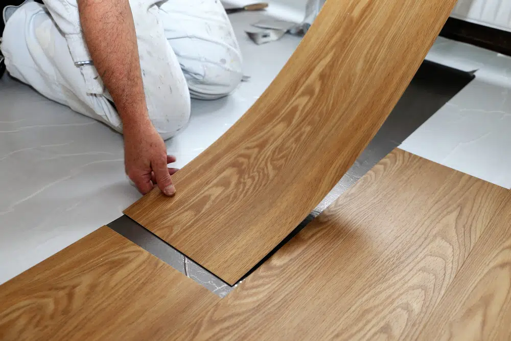 man layering sheet vinyl on subfloor