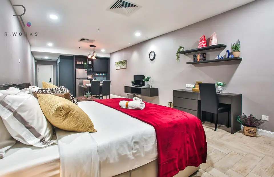 Dark wood work desk in front of the bed in the studio unit of Empire City Damansara