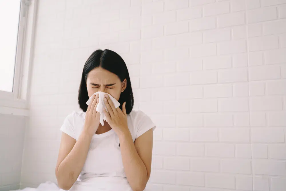 Woman sneezing due to allergies from dusty curtains