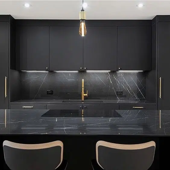 Black kitchen cabinetry with gold cabinet door handles and sink fixtures 